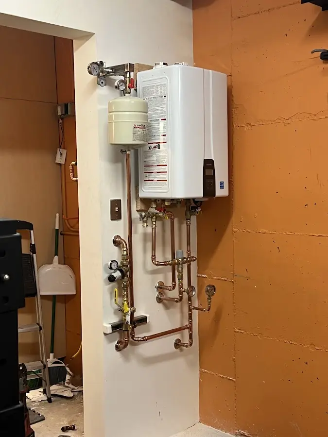 Plumbing technician inspecting water heater connections in North Wales